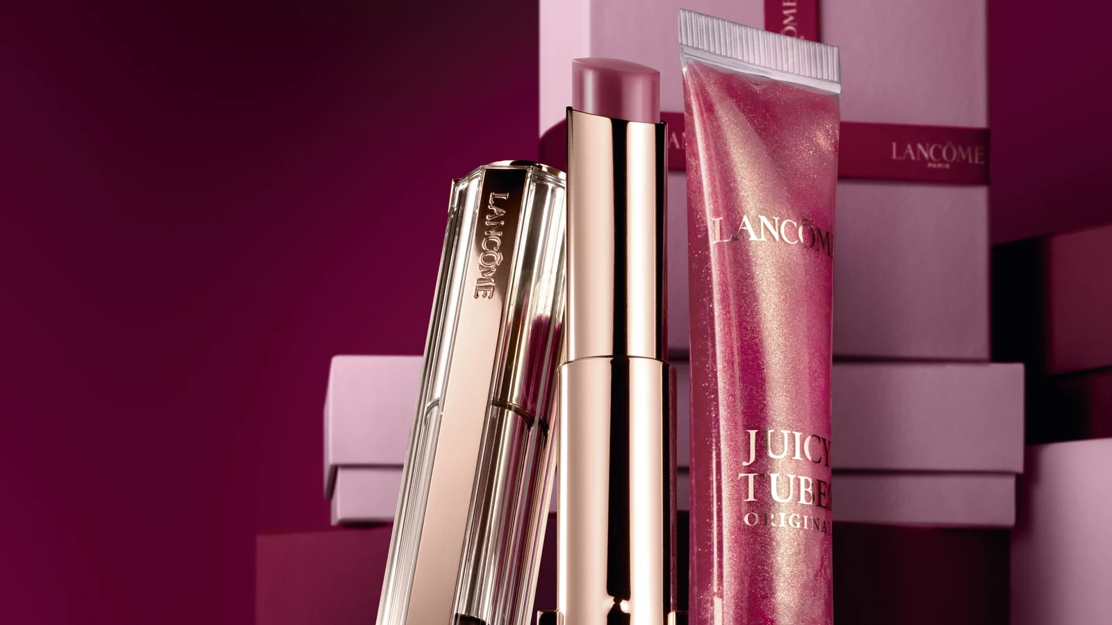 Lancôme Lip Idôle lip duo photographed on a burgundy set with pink gift boxes